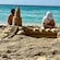 Two boys using tools to make a large sandcastle